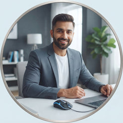 A professional portrait of Arjun Khanna in a modern home office setting with a computer mouse on his desk.